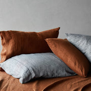 Pile of indigo chambray and sienna pillows, sienna