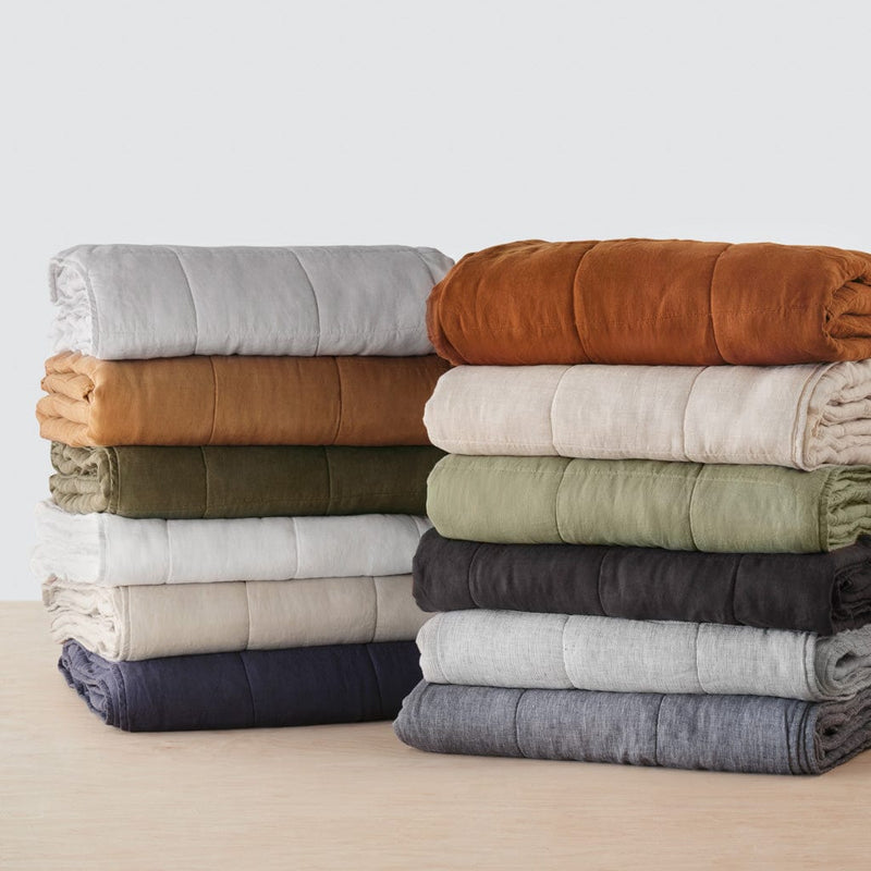 Stack of folded quilts in various colors, camel