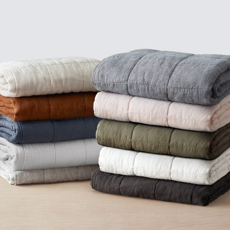 Stack of folded quilts in various colors, charcoal