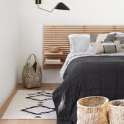 Charcoal linen quit folded at foot of styled bed, charcoal