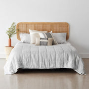 Graphite thin stripe linen quilt on styled bed with rattan headboard, graphite-thin-stripe