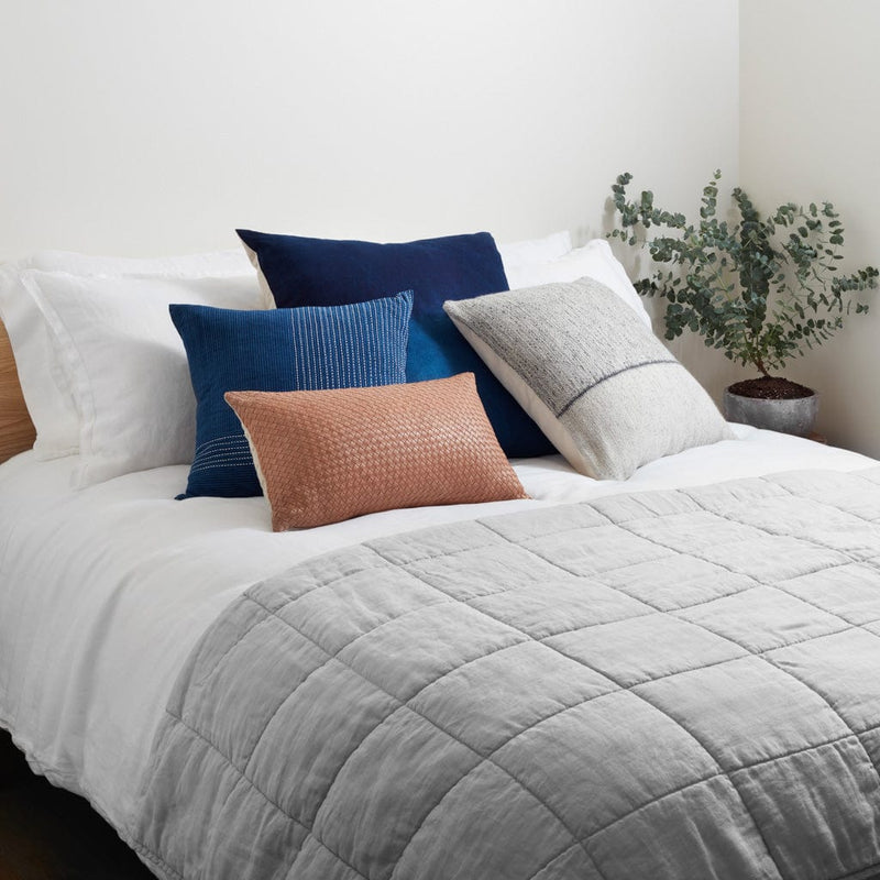 Light grey linen quilt folded at end of bed, light-grey