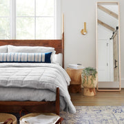 Styled bedroom with indigo dyed lumbar and light grey linen quit folded at end of bed, light-grey
