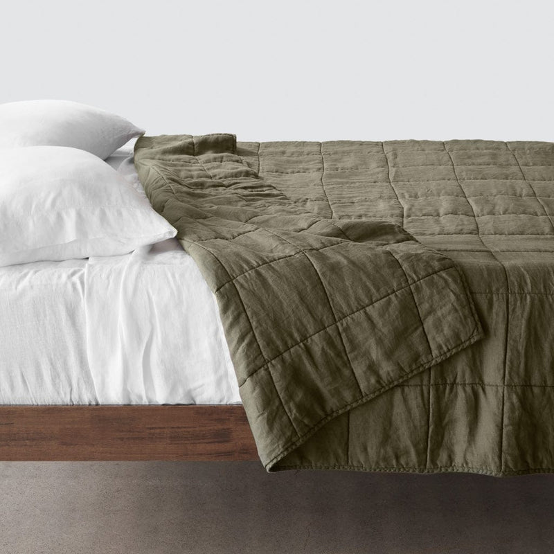 Side of bed with olive green stonewashed linen quilt, olive