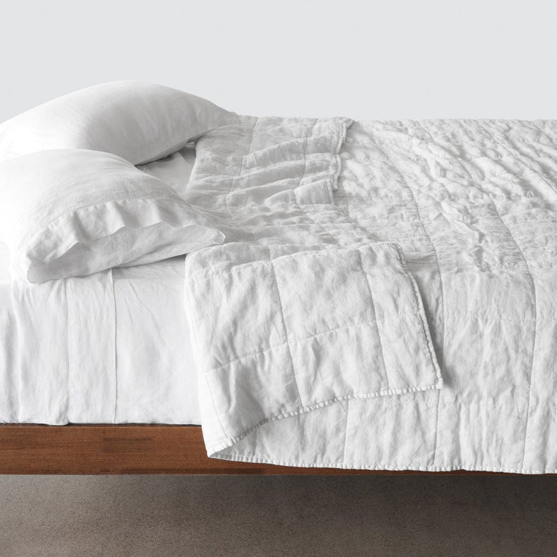 Side of bed with white stonewashed linen quilt, white
