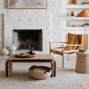 Chunky rug styled in living room with wicker furniture, ecru