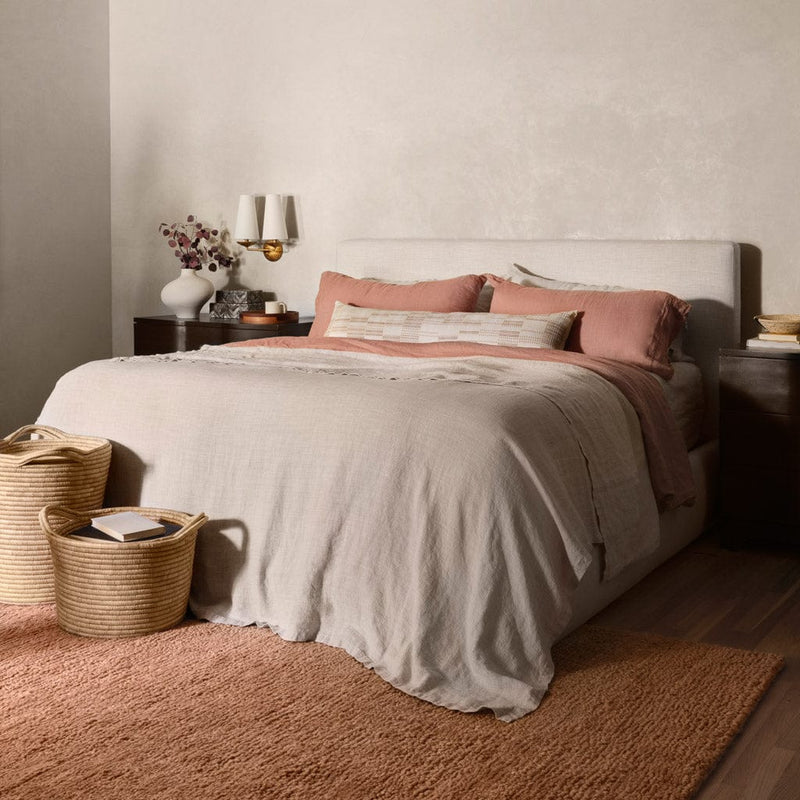 Suhana textured wool rug under neutral upholstered bed, rose-clay