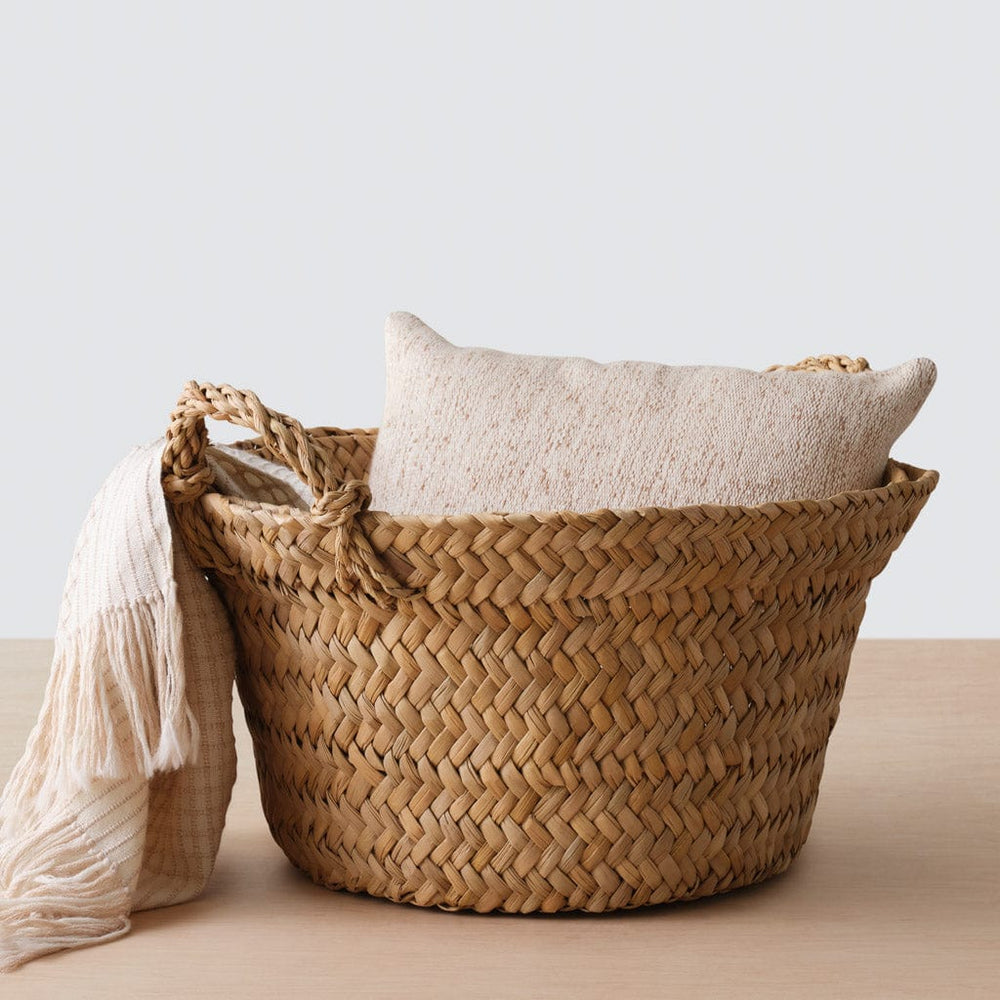 Throw pillow and blanket draped on woven floor basket