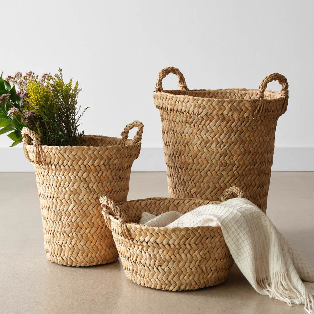 Woven floor basket with throw next to woven storage basket