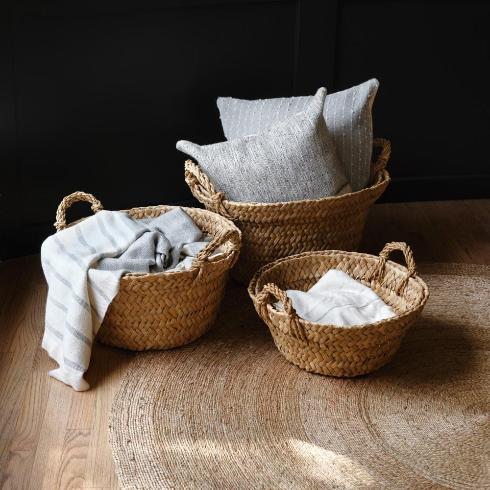 Woven floor baskets with throw pillows and blankets