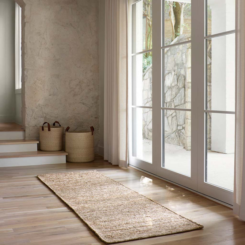 Jute rug styled on hardwood floor in modern hallway, dark
