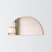 Bronze mirror shaped like half moon hanging on wall