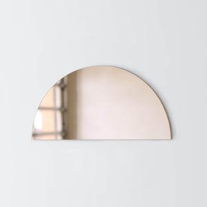 Bronze mirror shaped like half moon hanging on wall